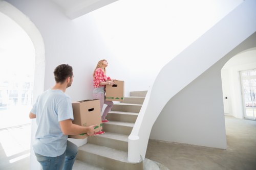 Removal crew carrying furniture through a narrow stairwell in Fulham